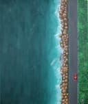 A bird's eye view of the coast, with a red Porsche on the road